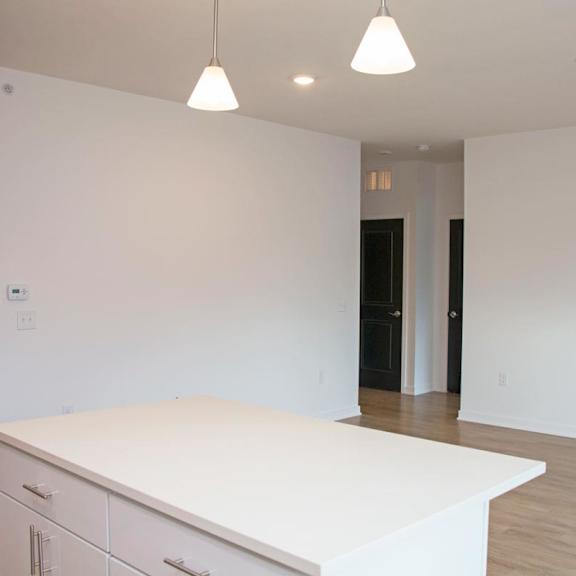 Thumbnail 5 of 8 A white kitchen island with a countertop and cabinets in a room with a black door.