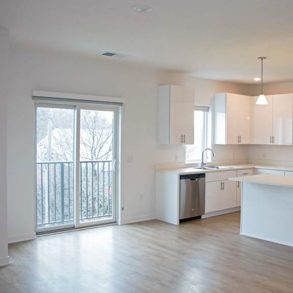 Thumbnail 2 of 8 A kitchen with white cabinets and a large island.