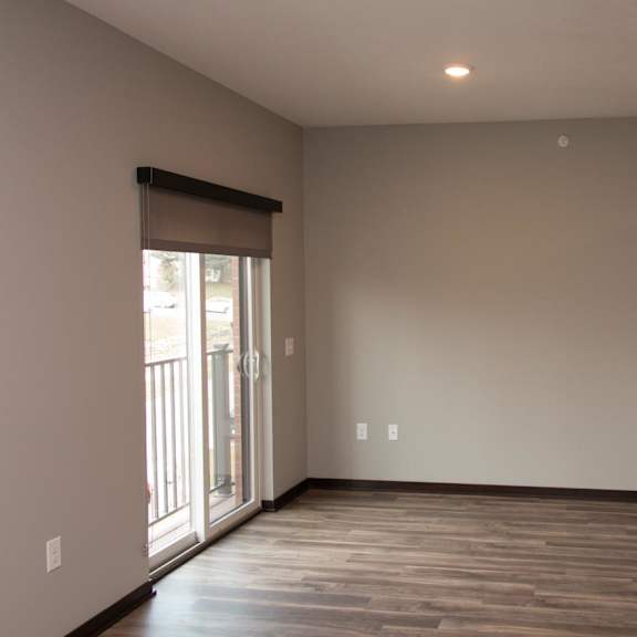 Thumbnail 3 of 6 A studio living space with wooden flooring and a sliding glass door.