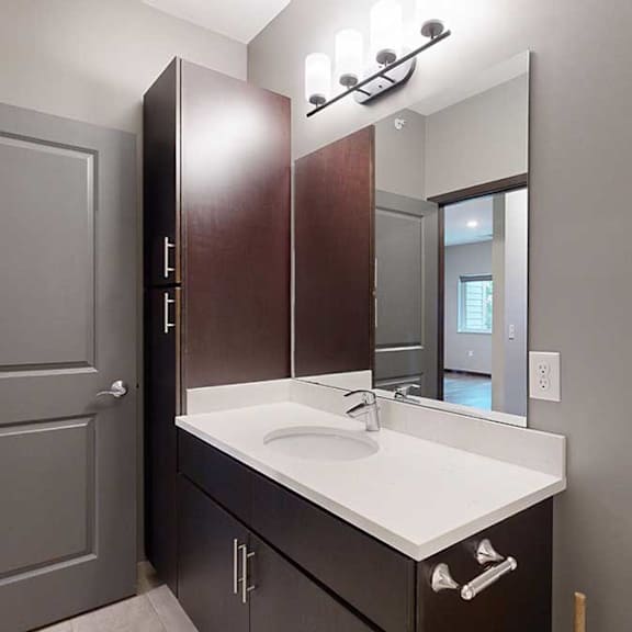 Thumbnail 18 of 21 a bathroom with dark storage cabinets, a large vanity sink, and light granite countertops