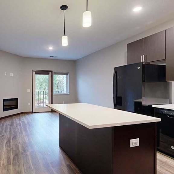 Thumbnail 6 of 21 a kitchen island with granite countertop next to a living room and a hallway to the bedroom