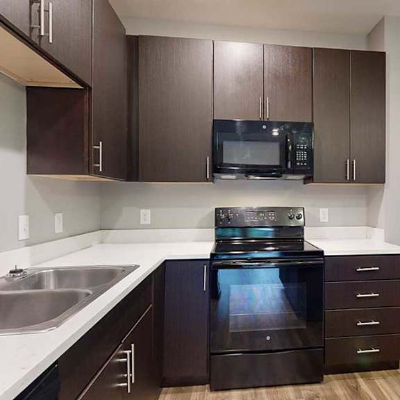 Thumbnail 3 of 21 a kitchen with a black oven and microwave, and dark brown cabinets