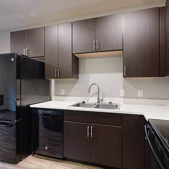 Thumbnail 4 of 21 a kitchen with dark cabinets, light granite countertops, and a black fridge