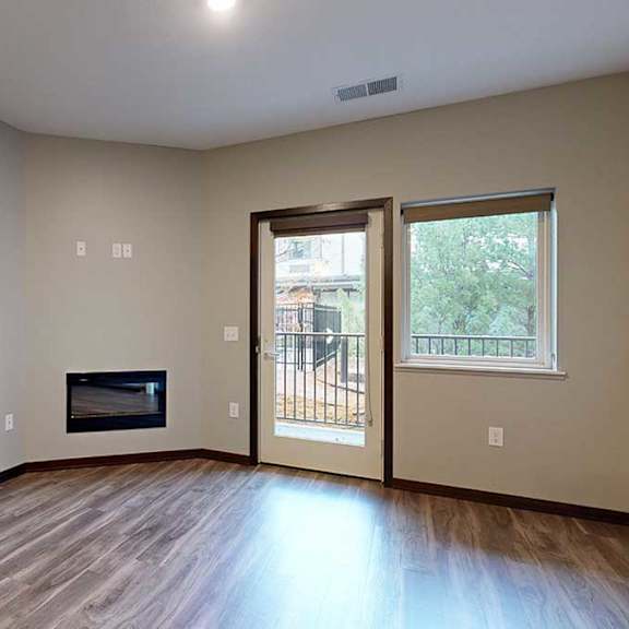 Thumbnail 9 of 21 a living room with a fireplace, and a glass door and window looking out to the patio