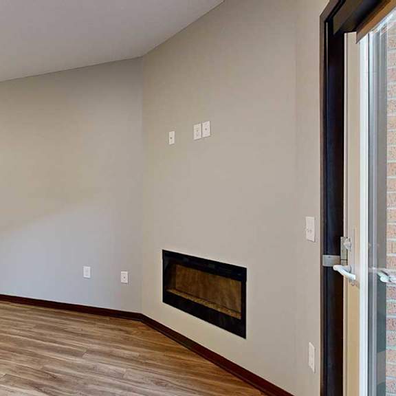 Thumbnail 12 of 21 a living room with hardwood floors, an electric fireplace, next to an open kitchen