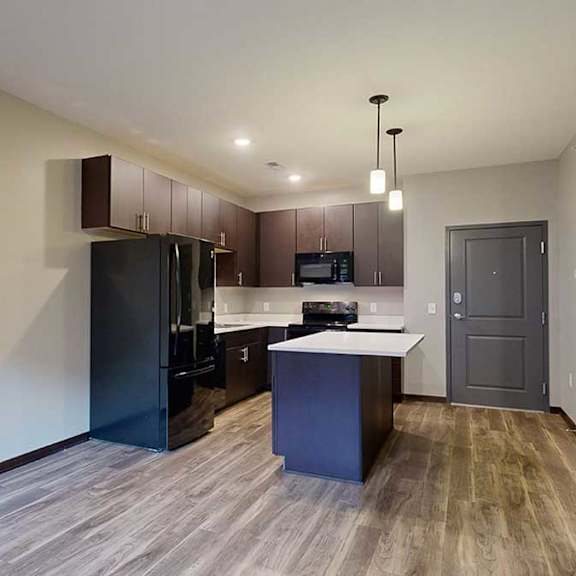 Thumbnail 8 of 21 an open-concept living room and kitchen with dark cabinets and black appliances
