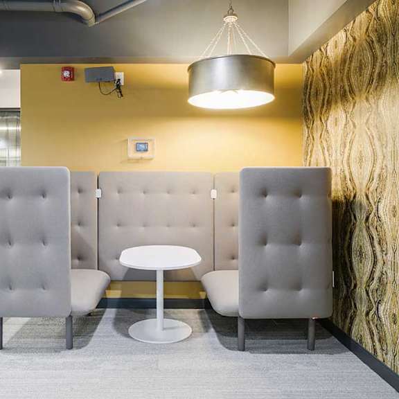 a modern cushioned booth with a  central table and walls for privacy