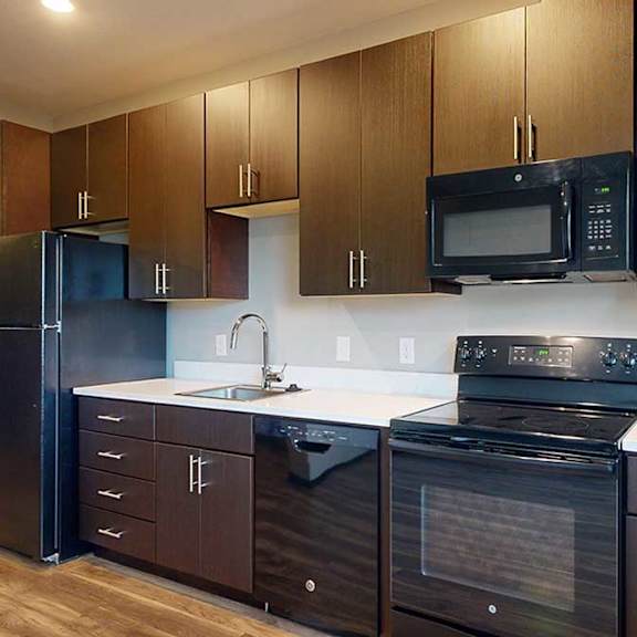 Thumbnail 11 of 17 a kitchen with dark wood cabinets, white granite countertops, and black appliances