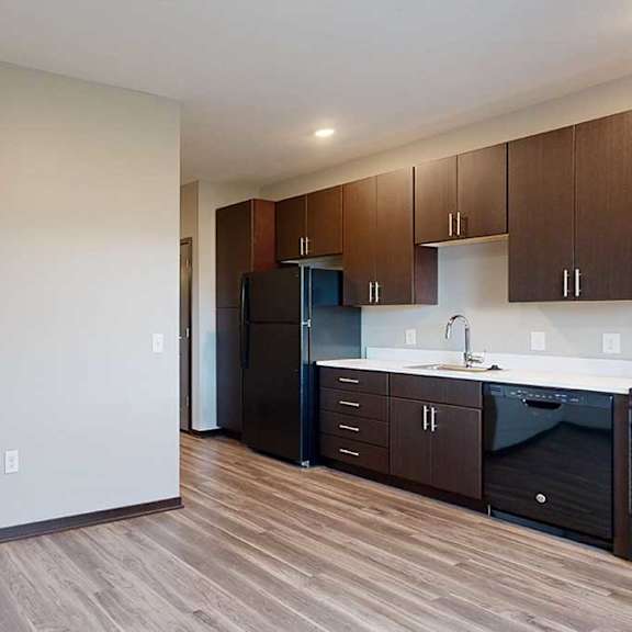 Thumbnail 10 of 17 a kitchen with dark wood cabinets next to a living area with hardwood floors