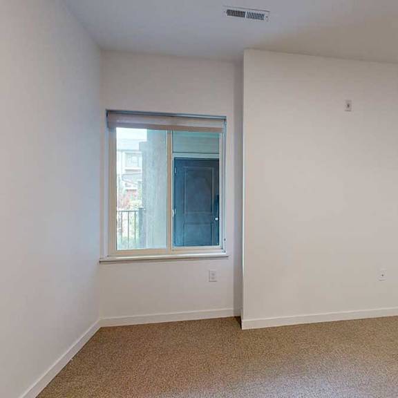 Thumbnail 23 of 28 a bedroom with a window looking out to the patio and carpet flooring
