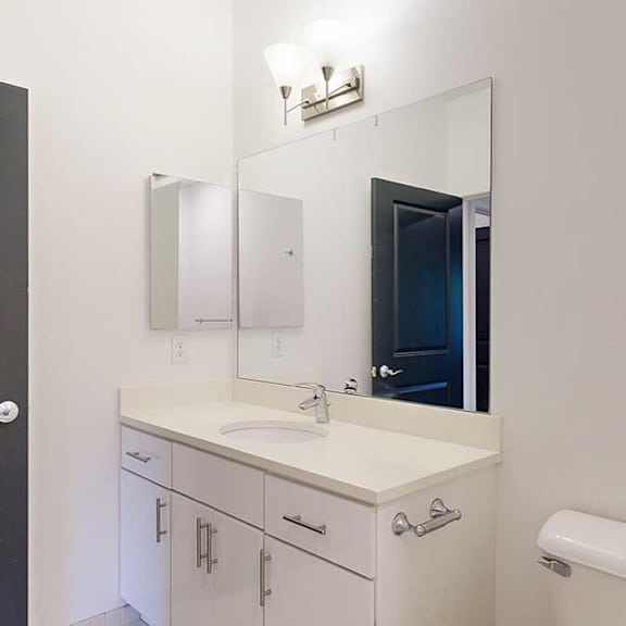 Thumbnail 26 of 28 an attached bathroom with a granite vanity sink, a large mirror, and a medicine cabinet
