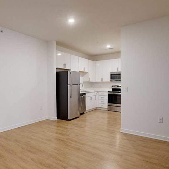 Thumbnail 15 of 28 a dining area with hard wood floors in front of a modern kitchen with white cabinets and stainless steel appliances