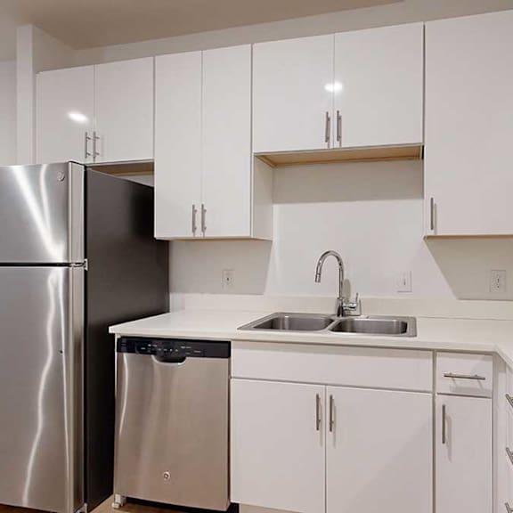 Thumbnail 18 of 28 a kitchen with white cabinets and a stainless steel refrigerator next to a stainless steel sink
