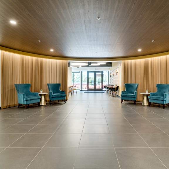 an open apartment lobby with blue chairs and a wooden ceiling.