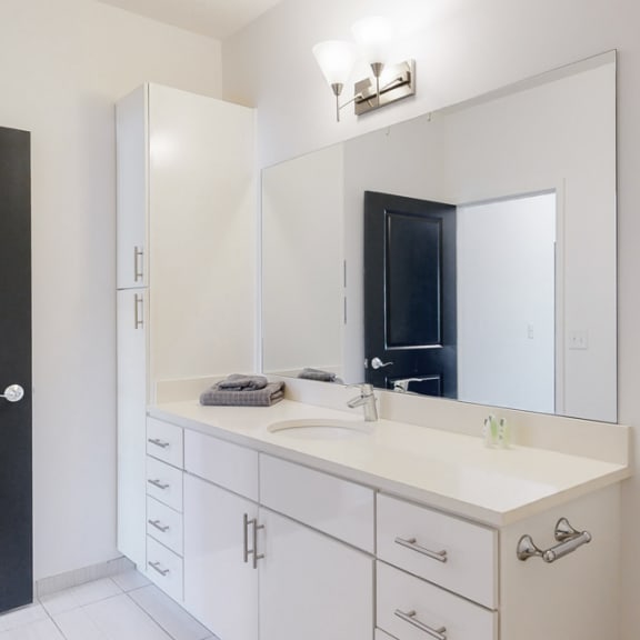 Thumbnail 10 of 15 Furnished apartment bathroom with large white vanity and left side storage cabinet