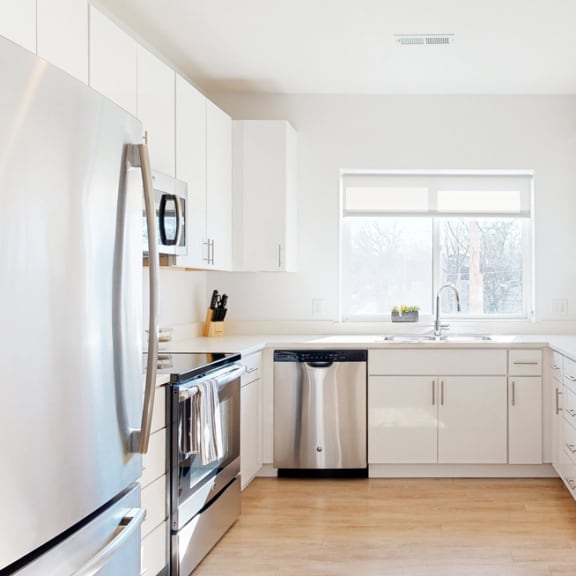 Thumbnail 6 of 15 Furnished apartment kitchen with white finish style and stainless steel appliances