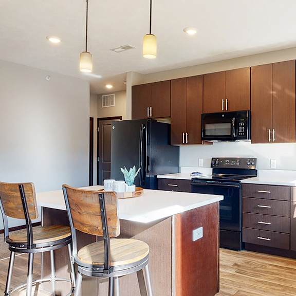 Thumbnail 5 of 9 a kitchen with dark brown wooden cabinets and a bar with two chairs