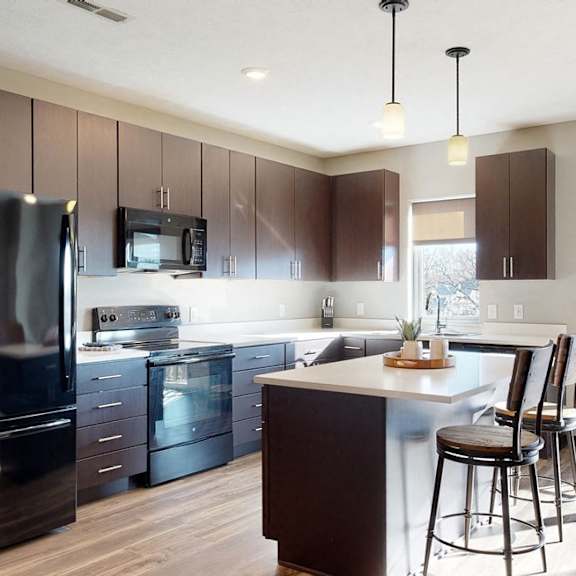 Thumbnail 4 of 9 Furnished apartment kitchen with dark finish style and all black kitchen appliances
