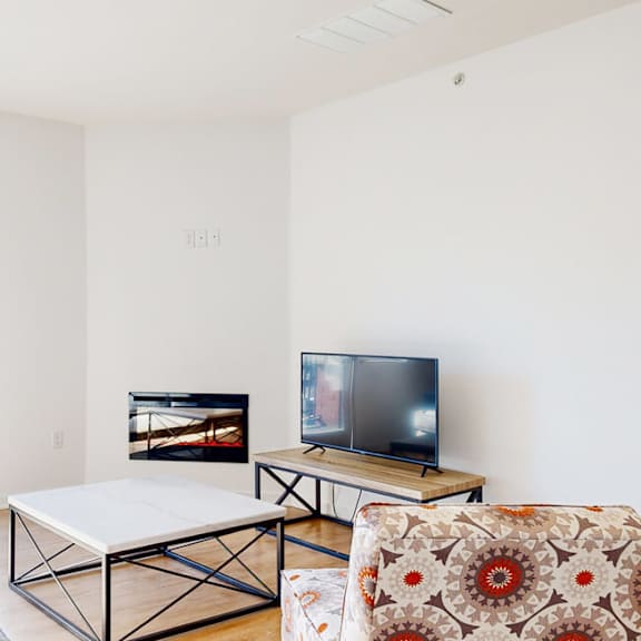 a living room with a couch, a coffee table, fireplace, and a television.