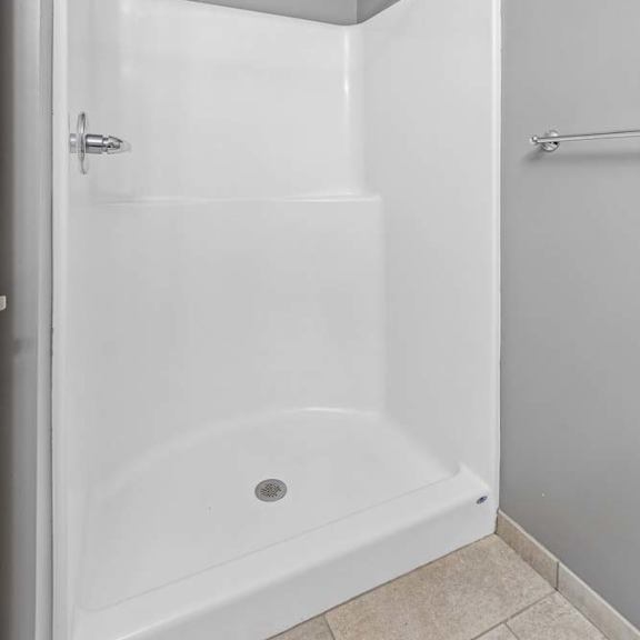 Thumbnail 15 of 15 Apartment bathroom with a walk-in shower, neutral finishes, and a shower curtain rod.