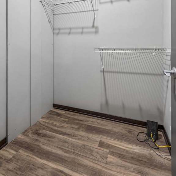 Thumbnail 13 of 15 Walk-in apartment closet with wood-style flooring and built-in wire shelving for organized storage.