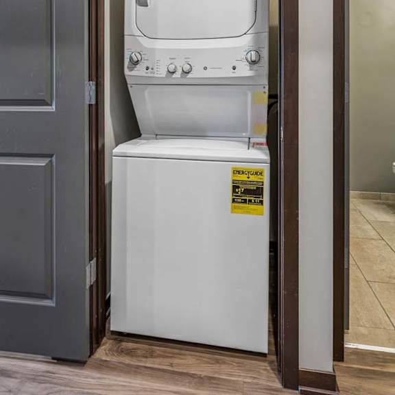 Thumbnail 12 of 15 In-home apartment laundry closet with a stacked washer and dryer, conveniently tucked behind bi-fold doors.