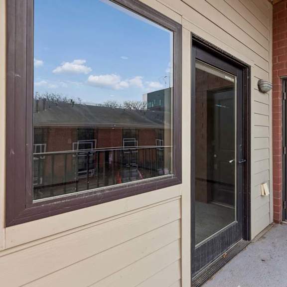 Thumbnail 33 of 34 Covered apartment entry patio with a private front door, large window, and brick exterior.