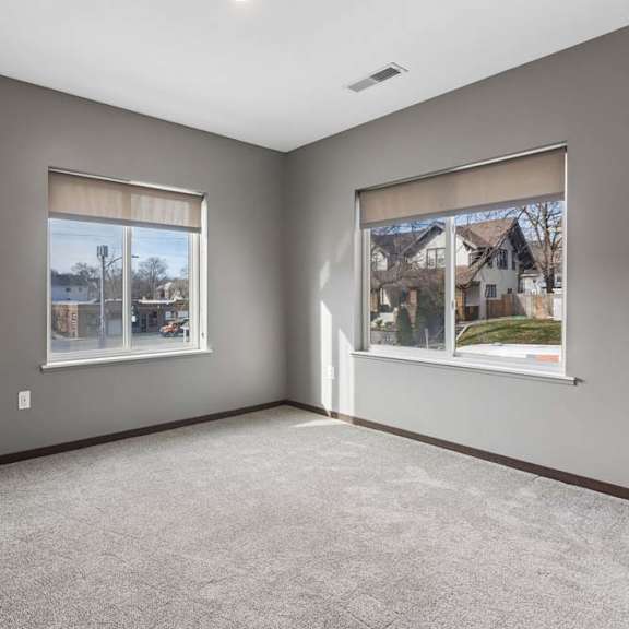 Thumbnail 27 of 34 Spacious apartment bedroom with soft carpeting, two large windows, and abundant natural light.