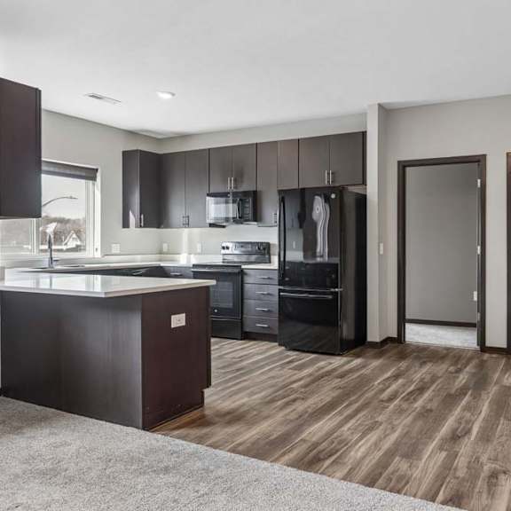 Thumbnail 21 of 34 Open-concept apartment with a modern kitchen, dark wood cabinetry, wood-style flooring, and a spacious living area.