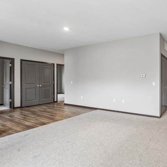 Thumbnail 24 of 34 Spacious apartment living room with plush carpeting, recessed lighting, and an open layout connecting to the kitchen and entryway.