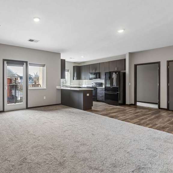 Thumbnail 23 of 34 Bright apartment living room with plush carpeting, a modern kitchen, recessed lighting, a fireplace, and a sliding glass door to a private patio.