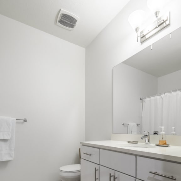 Thumbnail 8 of 8 Contemporary bathroom with white cabinetry and white quartz countertops at The Conrad apartments