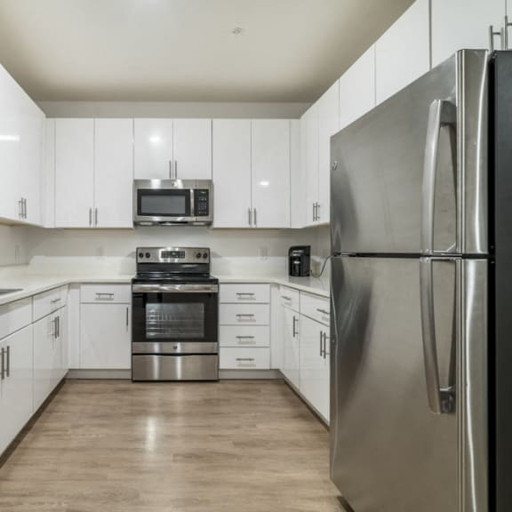 Thumbnail 3 of 8 Contemporary kitchen with white cabinetry, quartz countertops and stainless steel appliances at The Conrad