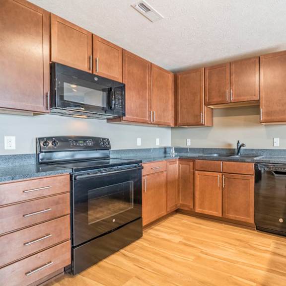 Thumbnail 4 of 24 Large U-shaped kitchen with warm brown cabinets, black appliances, grey granite