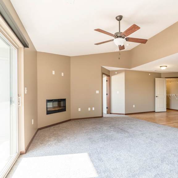 Thumbnail 7 of 24 A spacious living room with a fireplace and a ceiling fan.