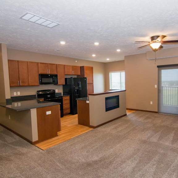 Thumbnail 3 of 14 A spacious kitchen with black appliances connected to a carpeted living room