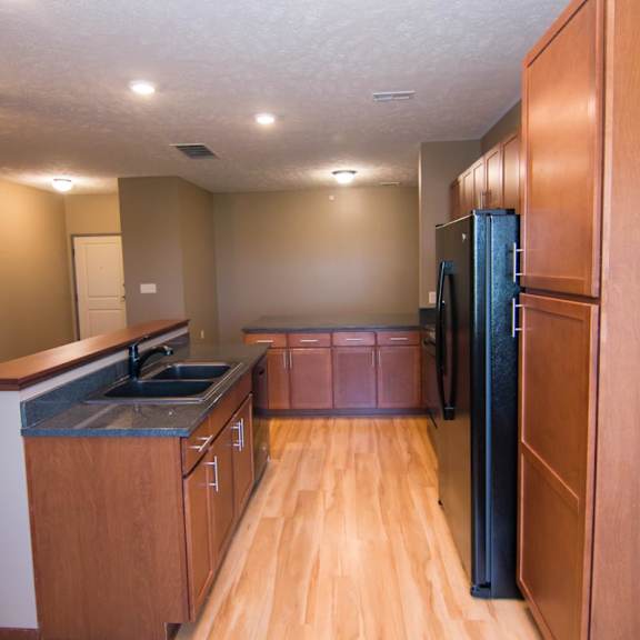 Thumbnail 6 of 14 A kitchen with wooden cabinets and a black refrigerator.