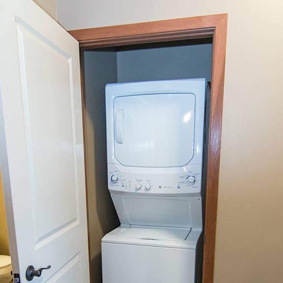 Thumbnail 14 of 14 A white washing stacked washer and dryer is in a small closet.