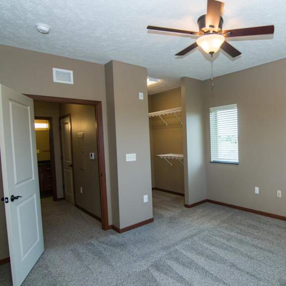 Thumbnail 10 of 14 A room with a ceiling fan, open walk in closet, and carpeted floor.