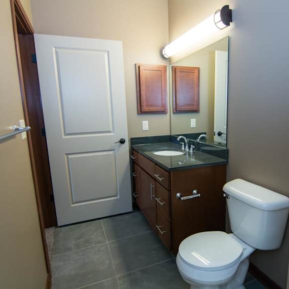 Thumbnail 13 of 14 A bathroom with a toilet, sink, and mirror.