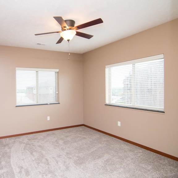 Thumbnail 8 of 9 A room with a ceiling fan and two windows.