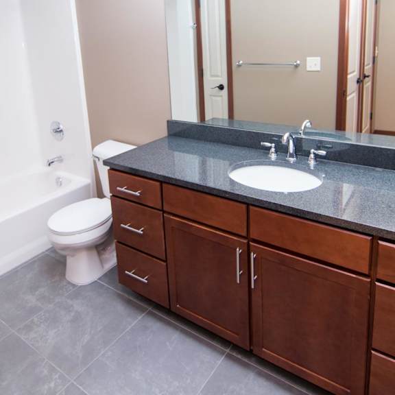 Thumbnail 9 of 9 A bathroom with a toilet, vanity with storage, and mirror.