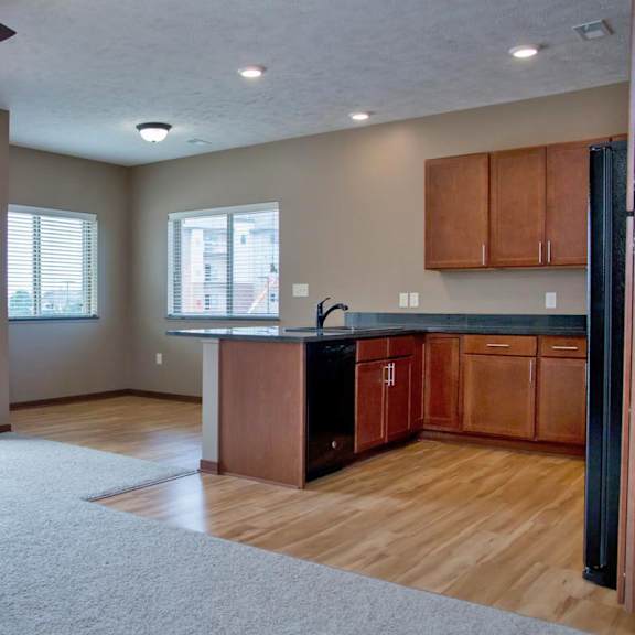 Thumbnail 3 of 13 A spacious kitchen and living room with wooden floors and a ceiling fan.