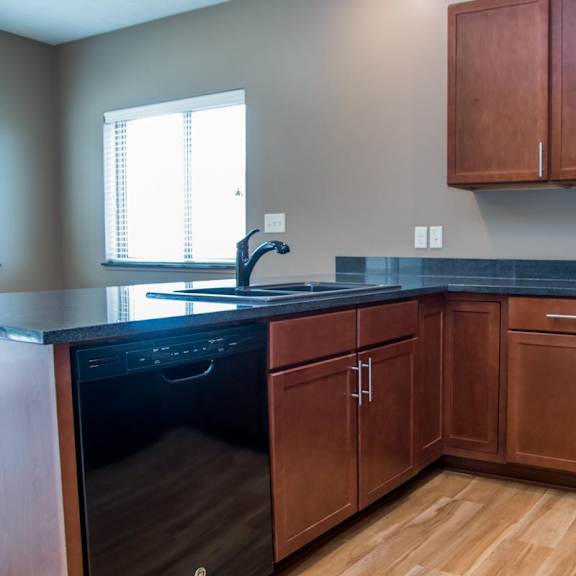 Thumbnail 6 of 13 A kitchen with brown cabinets and a black countertop.