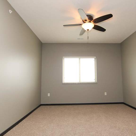 Thumbnail 8 of 14 A room with a ceiling fan and a window.