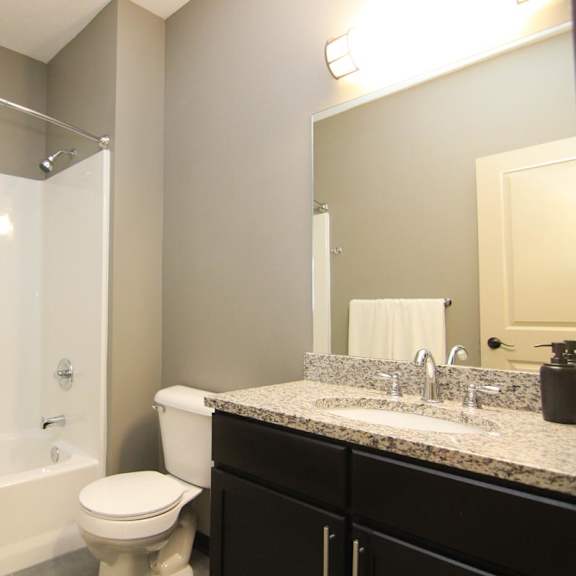 Thumbnail 12 of 14 A bathroom with a white toilet and a white bathtub.