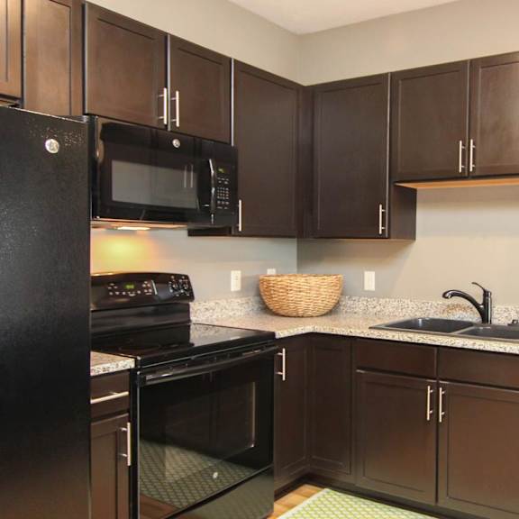 Thumbnail 17 of 24 A kitchen with black appliances and brown cabinets.