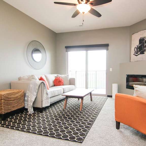 Thumbnail 19 of 24 A living room with a white couch, a black and white rug, and an orange chair.