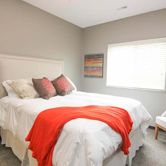 Thumbnail 21 of 24 A bedroom with a white bed and a red blanket.