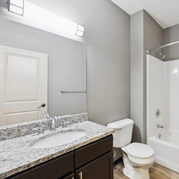 Thumbnail 28 of 33 A bathroom with a granite vanity sink and a tub shower.